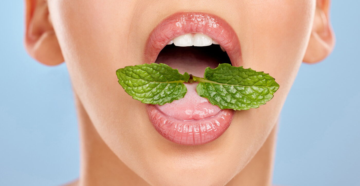 Wide open mouth with mint leaves in tongue